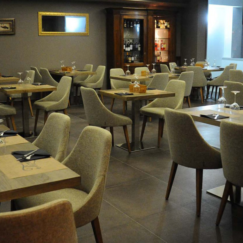 Armlehnstuhl Modell KONTEA 590 von Et al. – eleganter Polsterstuhl mit hoher Rückenlehne und Buchenholzgestell für stilvolle Restaurants und Hotels - Hantermann - Der Hotelausstatter Restaurant mit vielen KONTEA-590-Armlehnstühlen in hellgrauem Stoff und Holzbeinen an quadratischen Holztischen
