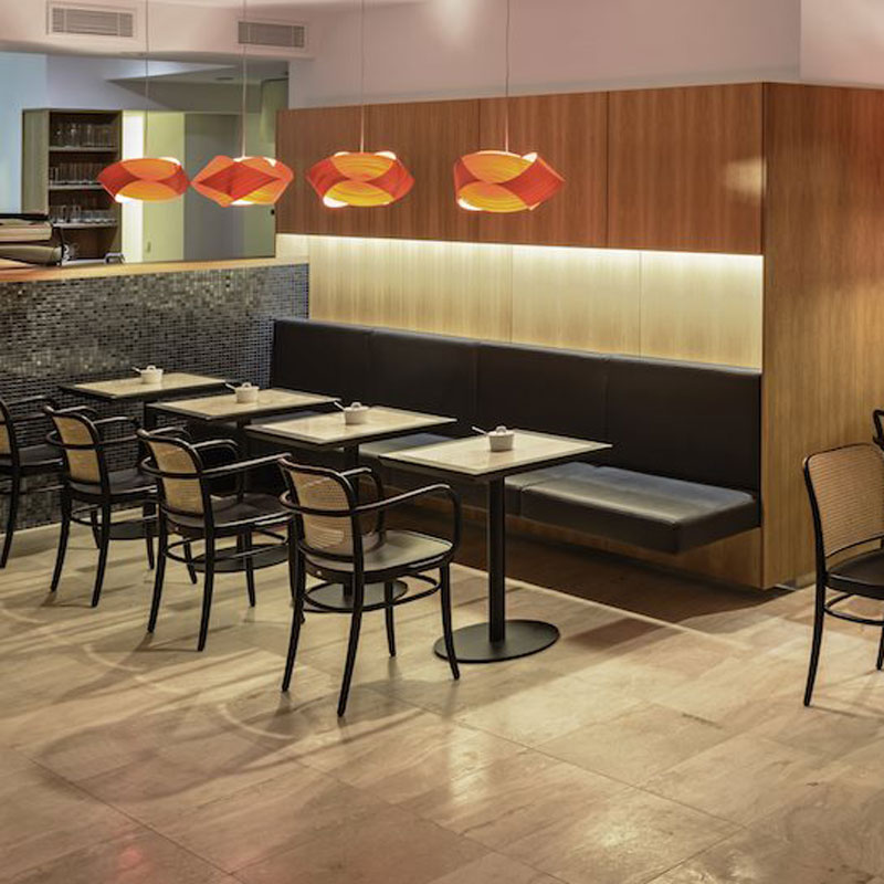 Bugholz Restaurantstuhl Modell 811 von TON – klassischer Caféstuhl mit Wiener Geflecht im modernen Gastroambiente - Hantermann - Der Hotelausstatter Café mit Bugholz Restaurantstühlen Modell 811 von TON, Wiener Geflecht, schwarzen Sitzpolstern und roten Pendelleuchten über Wandbank