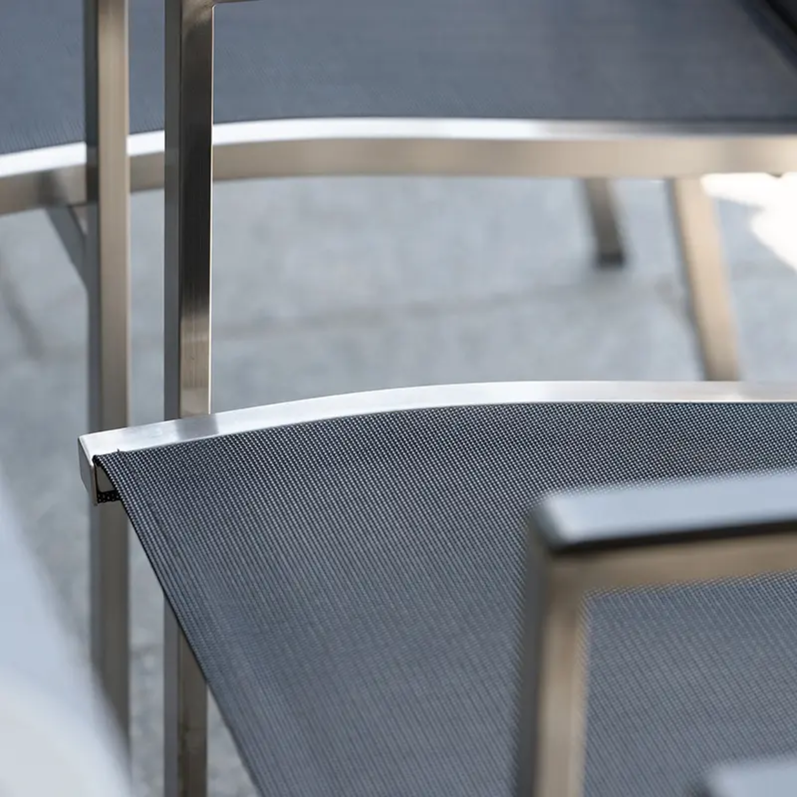 CARDIFF Outdoor-Stapelsessel von STERN® – komfortables Textilen auf Edelstahlgestell - Hantermann - Der Hotelausstatter Detailansicht des CARDIFF Outdoor-Stapelsessels von STERN® mit silbergrauem Textilen, Edelstahlrahmen und Armlehne
