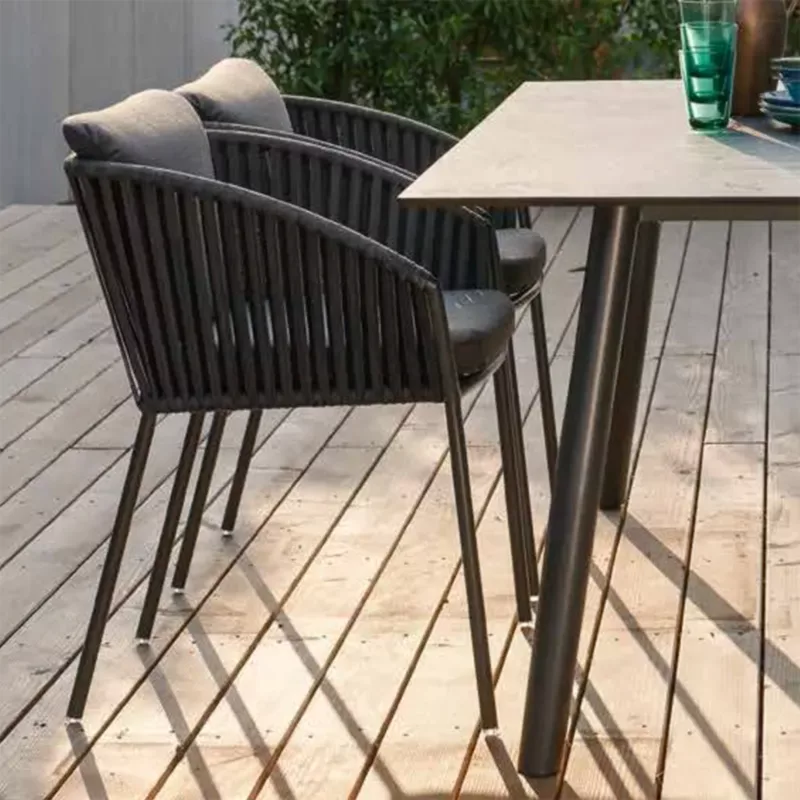 CLIFF Outdoor Stapelsessel von STERN® in Dunkelgrau mit Gurtbespannung und Sitzkissen am Terrassentisch