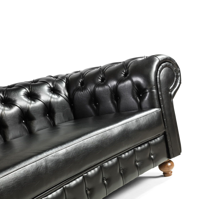 Detail Chesterfield Sofa Nr. 11 – Rücken- und Sitzpartie der geschwungenen Ledercouch - Hantermann - Der Hotelausstatter Detailansicht Chesterfield Sofa Nr. 11, schwarze Ledercouch mit tiefgesteppter Rückenlehne, Rolllarmlehne und gepolsterter Sitzfläche, Holzfuß unten rechts