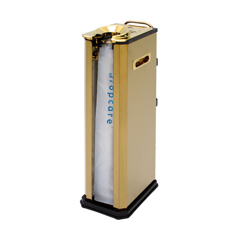 dropcare® Regenschirmtüten-Spender in Gold für Hotels - Hantermann - Der Hotelausstatter dropcare® Regenschirmtüten-Behälter in Gold mit einem Spenderbereich, transparenter wiederverwendbarer Regenschirmtüte mit blauem dropcare® Schriftzug, goldfarbener Entnahmeöffnung, seitlichem Griff und schwarzem Sockel vor weißem Hintergrund