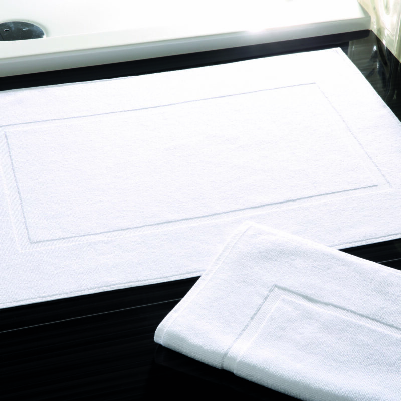 LESBOS Badvorleger 50×70 cm aus 600 g/m² Walkfrottier in Weiß vor Dusche im Hotelbad