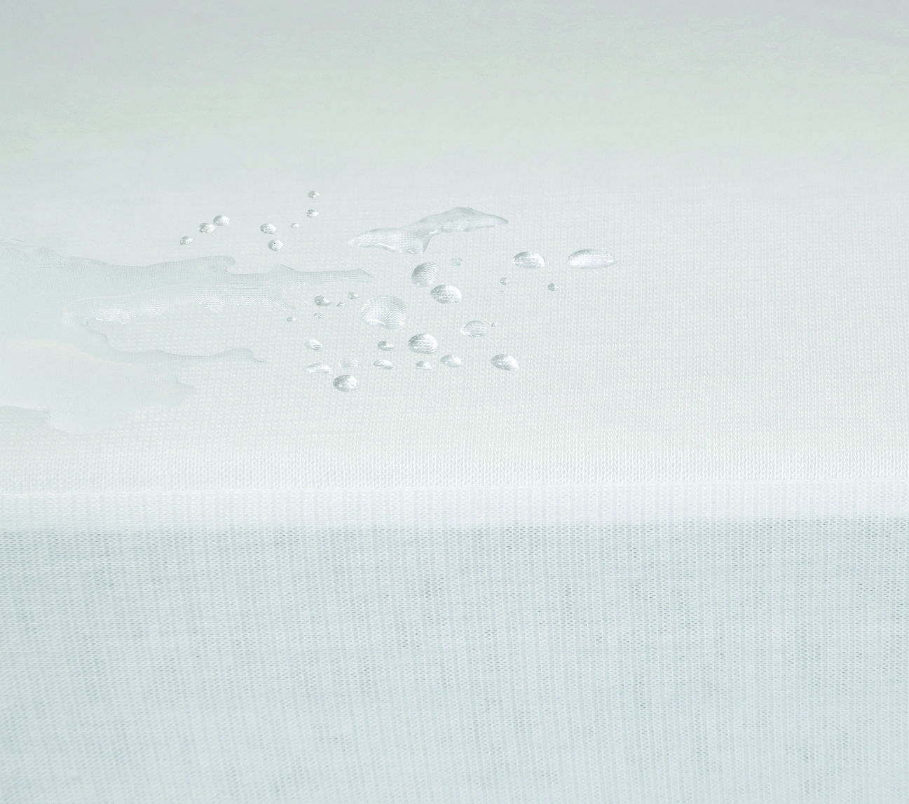 Matratzenschutz CARETEX© – milben- und wasserdichter Hygienebezug mit PU-Oberseite und PES-Unterseite, wischdesinfizierbar - Hantermann - Der Hotelausstatter Nahaufnahme CARETEX Matratzenschutz mit perlenförmig abperlenden Wassertropfen auf weißer, wasserdichter Oberfläche