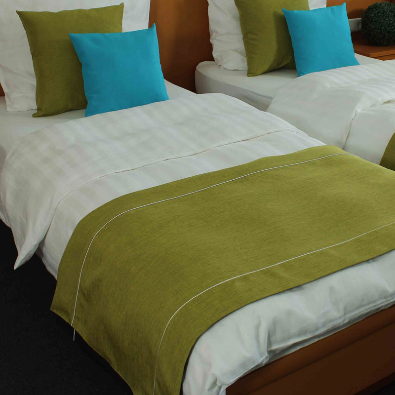 MIO Bettläufer/Fußplaid – frischer Hellgrün-Look mit türkisfarbenen Dekokissen - Hantermann - Der Hotelausstatter Zwei Hotelbetten mit weißer Bettwäsche, hellgrünem MIO Bettläufer und hellgrünen sowie türkisfarbenen Dekokissen