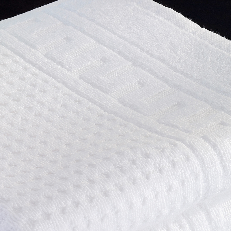 ROMA Zwirnfrottier – Detail der Bordüre und Waffel-Reliefstruktur von Handtuch & Badvorleger 430/660 g/m² - Hantermann - Der Hotelausstatter ROMA Zwirnfrottier: Nahaufnahme der weißen Bordüre mit Reliefstruktur und Waffeloberfläche