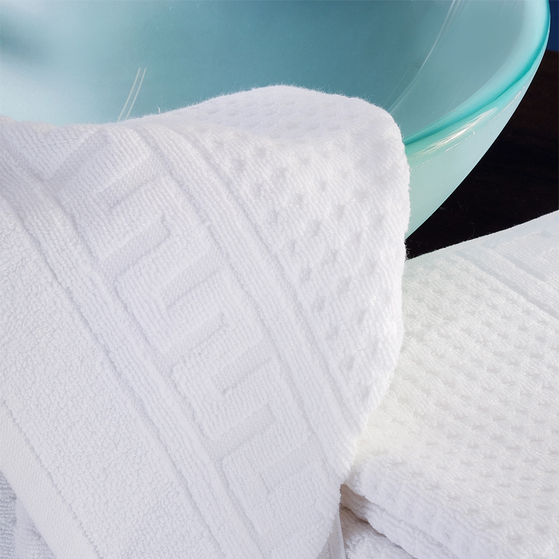 ROMA Zwirnfrottier – Handtuch-Detail mit Reliefbordüre und Waffelstruktur 430/660 g/m² am Waschbecken - Hantermann - Der Hotelausstatter ROMA Zwirnfrottier Handtuch mit Reliefbordüre und Waffelstruktur in Weiß vor Glaswaschbecken