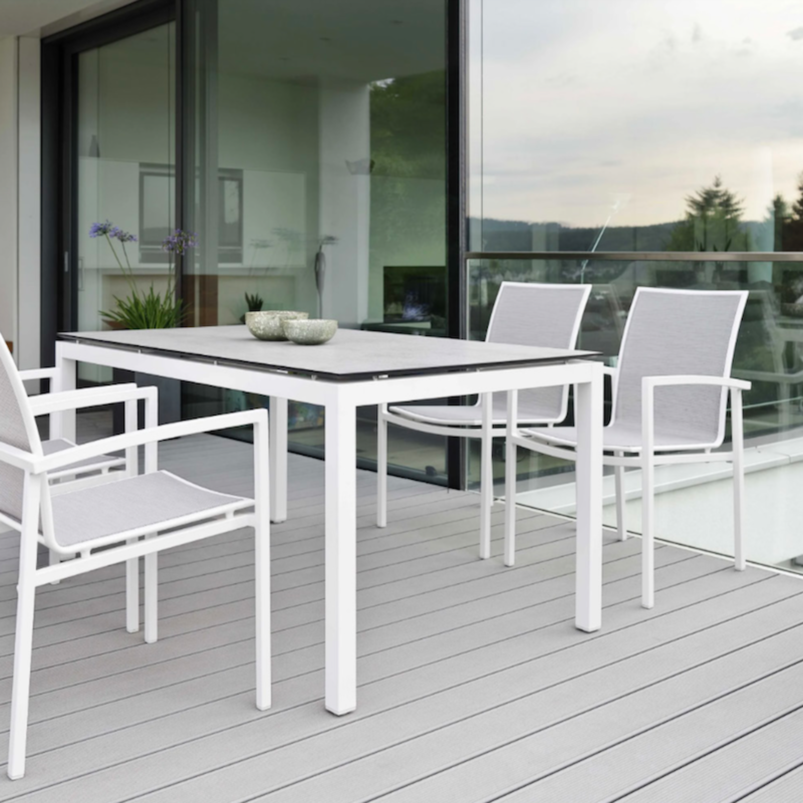 SKELBY Outdoor Stapelsessel auf moderner Terrasse - Hantermann - Der Hotelausstatter SKELBY Outdoor Stapelsessel von STERN® in Weiß mit grauer Bespannung an einem modernen Gartentisch