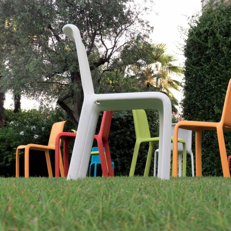 SNOW 300 Outdoor Stapelstuhl von Pedrali – bunte Kunststoffstühle aus Polypropylen für Garten-Events, Hotelanlagen & Terrassen - Hantermann - Der Hotelausstatter Mehrere SNOW 300 Outdoor Stapelstühle von Pedrali in Weiß, Orange, Rot und Grün auf einer Rasenfläche in Gartenumgebung