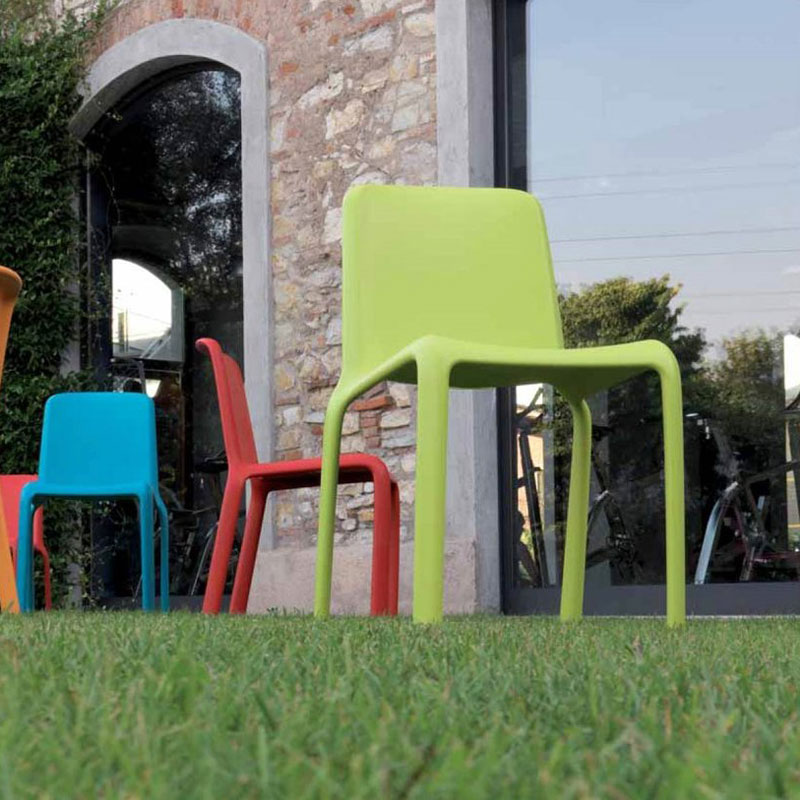 SNOW 300 Outdoor Stapelstuhl von Pedrali – farbenfroher Kunststoffstuhl aus Polypropylen für Garten, Terrasse & Gastroflächen - Hantermann - Der Hotelausstatter SNOW 300 Outdoor Stapelstühle von Pedrali in Grün, Rot und Blau auf der Wiese vor einer Terrasse, bunter Polypropylenstuhl