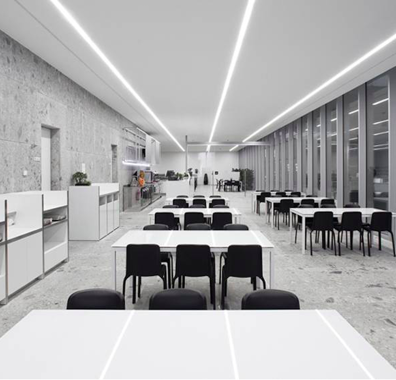 SNOW 300 Stuhl von Pedrali – stapelbarer Kunststoffstuhl in Schwarz für Kantine, Mensa & Betriebsgastronomie - Hantermann - Der Hotelausstatter Mehrere schwarze SNOW 300 Stühle von Pedrali in einer modernen Kantine mit weißen Tischen und langen Lichtbändern