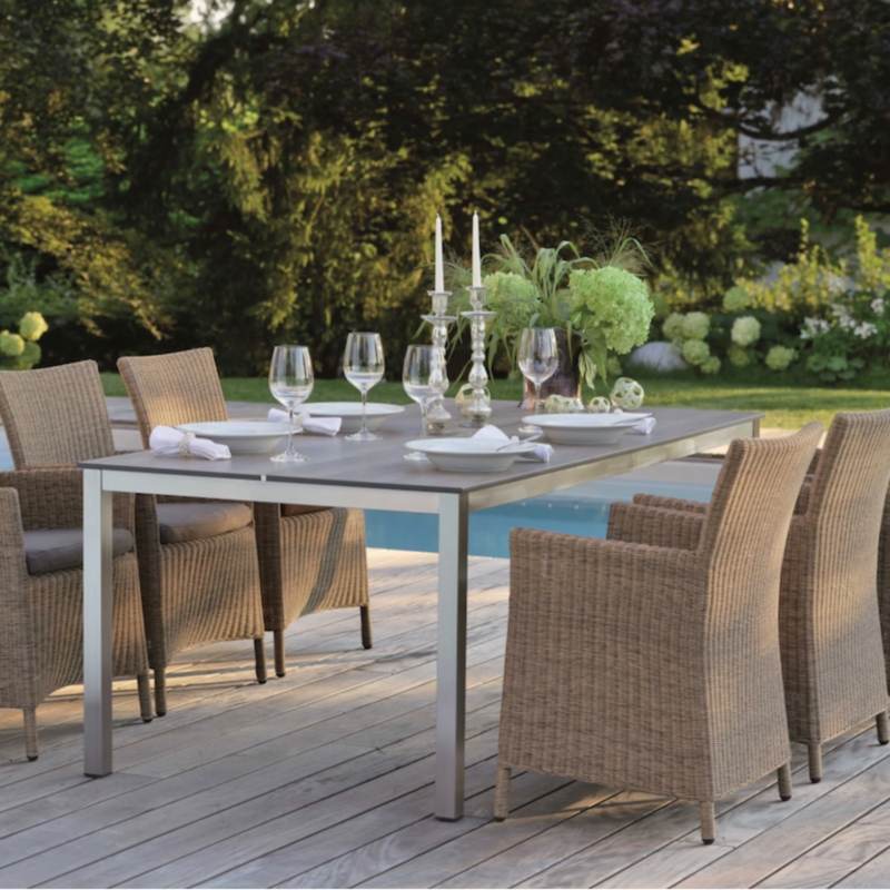 SORTINO Geflechtsessel von STERN® in Beige an gedecktem Outdoor-Esstisch auf einer Terrasse am Pool