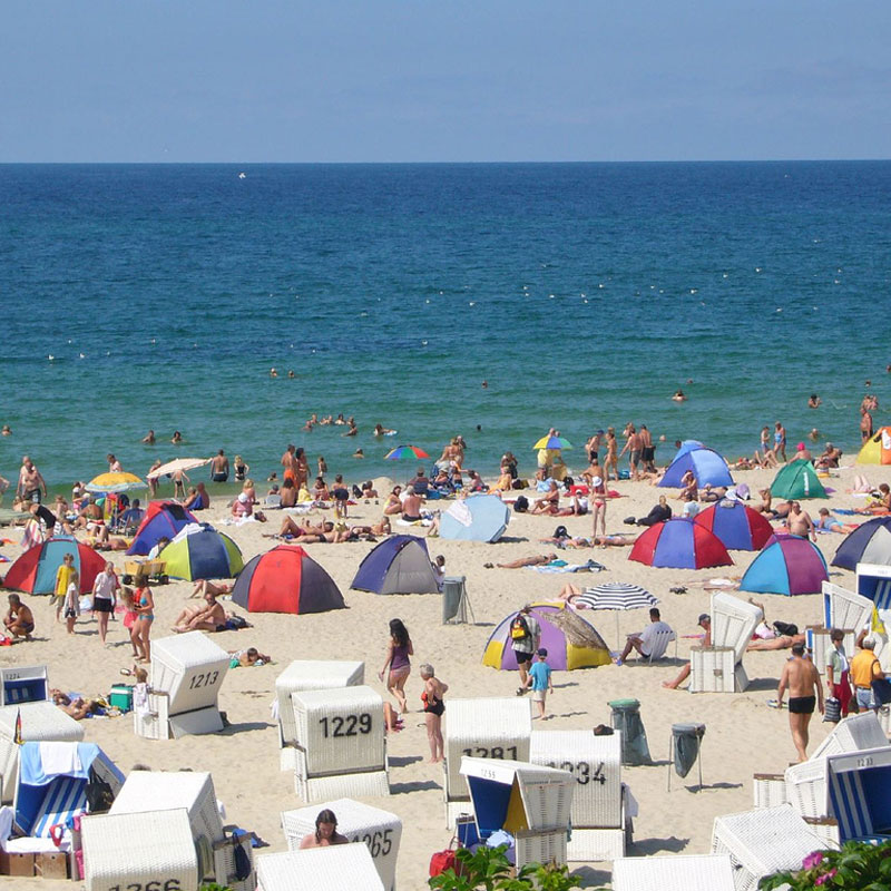 WESTERLAND Walkfrottier – farbenfrohe 440 g/m² Hotel-Handtücher mit 3-Streifen Webbordüre für Strand- und Spa-Bereiche - Hantermann - Der Hotelausstatter Strand mit Gästen und WESTERLAND 440 g/m² Walkfrottier-Handtüchern in vielen Farben und 3-Streifen Webbordüre