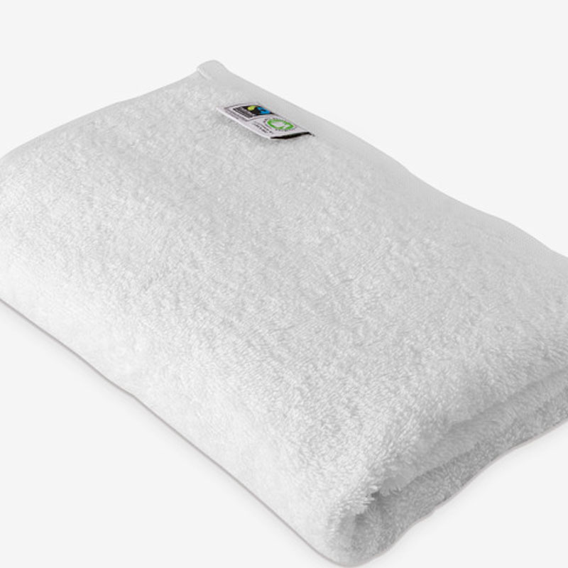 Das Bild zeigt ein weißes Frottierhandtuch, ordentlich zusammengelegt. Farbe: Reinweiß Material: Frottier – saugfähig, weich und flauschig, ideal für Bad und Wellness Design: Schlicht, ohne Bordüre oder Muster, klassisch zeitlos Besonderheit: Auf dem Etikett sichtbar sind zwei Zertifizierungen: GOTS (Global Organic Textile Standard): Bestätigung, dass das Handtuch aus Bio-Baumwolle gefertigt wurde und nachhaltig produziert ist. FAIRTRADE: Garantie für faire Handels- und Arbeitsbedingungen. 👉 Zusammengefasst: Ein nachhaltiges, hochwertiges weißes Handtuch aus Bio-Baumwolle, das ökologisch und fair produziert wurde – perfekt für ein bewusstes und komfortables Badeerlebnis.