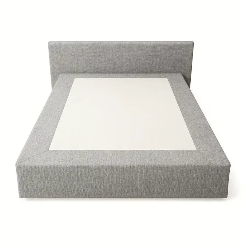 Das Bild zeigt ein modernes Boxspringbett mit einem grauen, textilen Überzug und bodenlangem Volant-Skirting. Das Design ist klar und geradlinig, ohne Falten an den Ecken. Die Stoffverkleidung wirkt hochwertig, das Kopfteil ist schlicht gehalten und die Linien des Bettes sind glatt für eine zeitgemäße Optik. Die helle mittlere Fläche hebt sich ab und verleiht dem Bett einen frischen, gepflegten Eindruck.