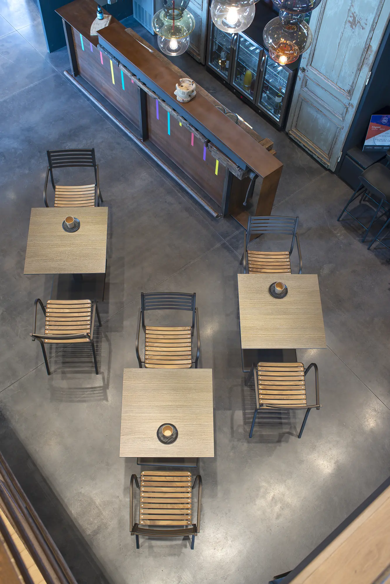 EMU SEGNO 267 Stapelsessel - Hantermann - Der Hotelausstatter Modernes Café-Ambiente mit quadratischen Holztischen und mehreren EMU SEGNO 267 Stapelsesseln mit Teakholzlatten-Sitz auf poliertem Betonboden, Draufsicht.