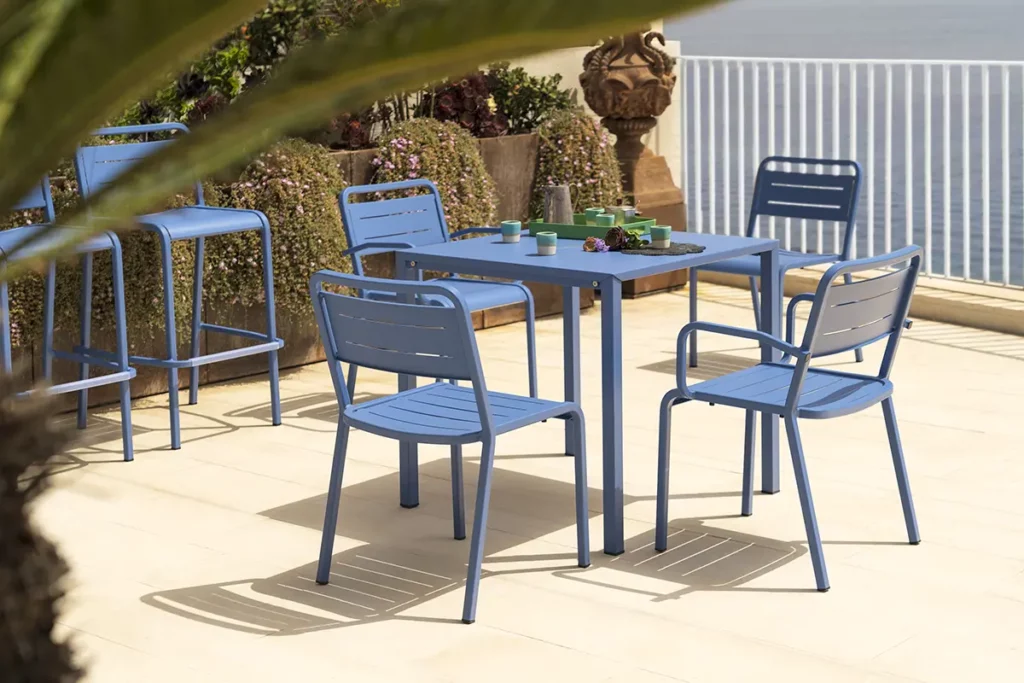 EMU Urban Aluminium Terrassenstuhl in Blau an modernem Outdoor-Bistroset mit Meerblick