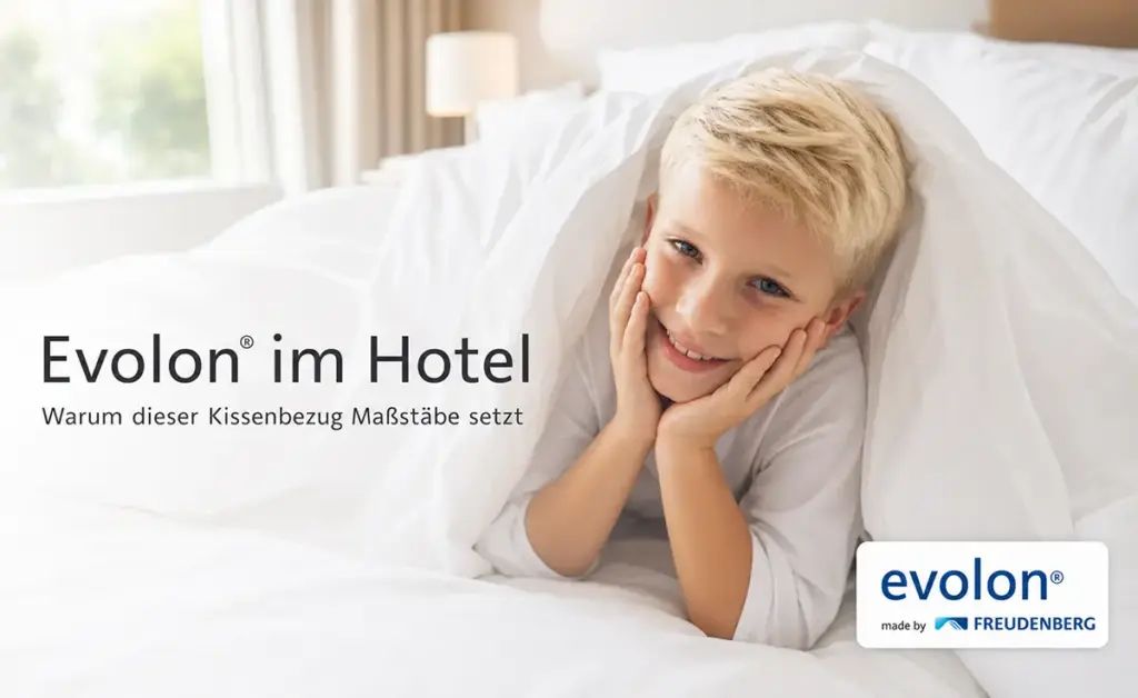 Kind kuschelt im weißen Hotelbett mit Evolon Kissenbezug und genießt allergiefreien, hygienischen Schlafkomfort